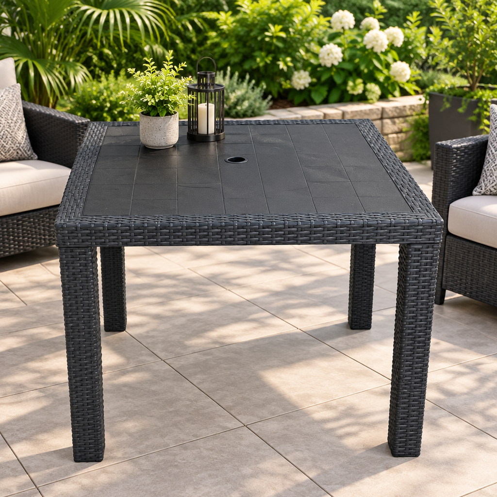 Dark rattan square outdoor patio table styled on a beautiful patio with lush greenery